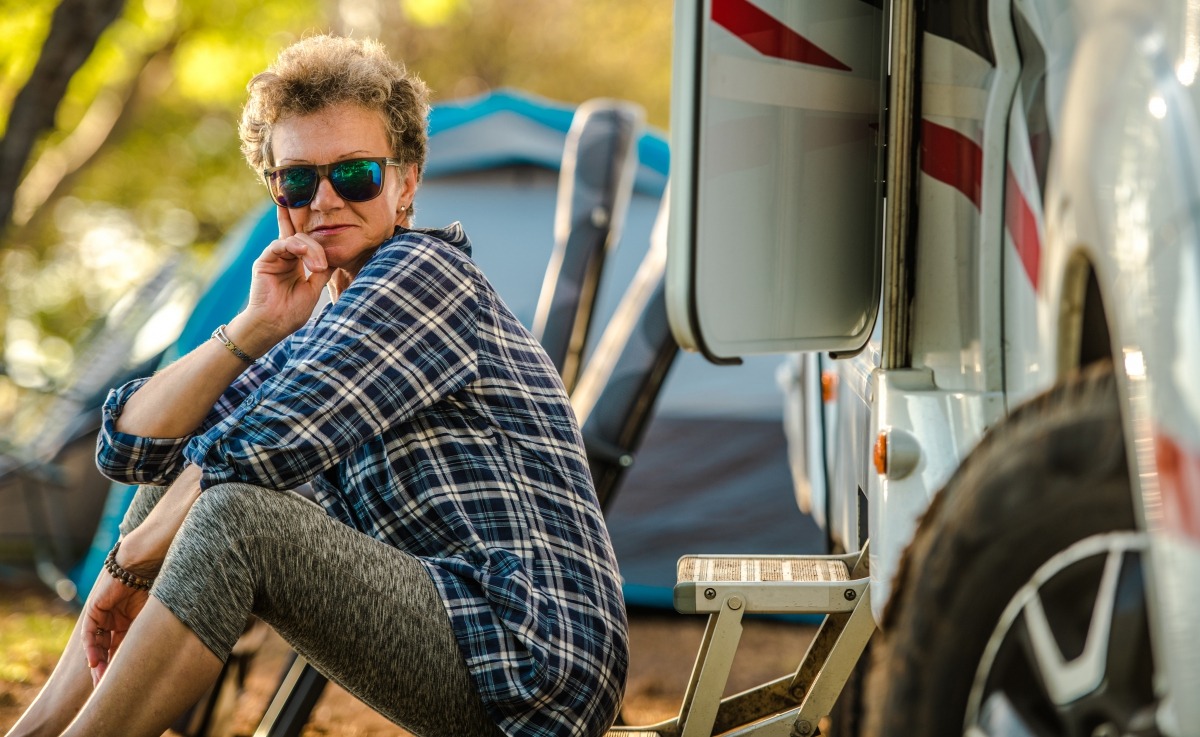 A older woman lounges outside of an RV